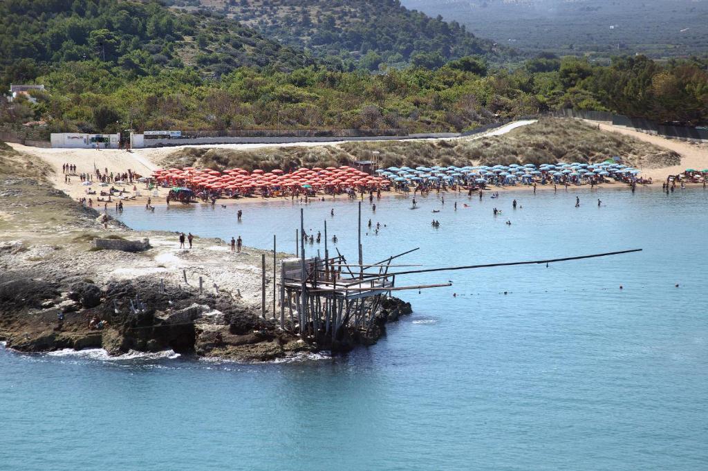 a beach with umbrellas and people in the water at Camping Village Baia Falcone in Vieste