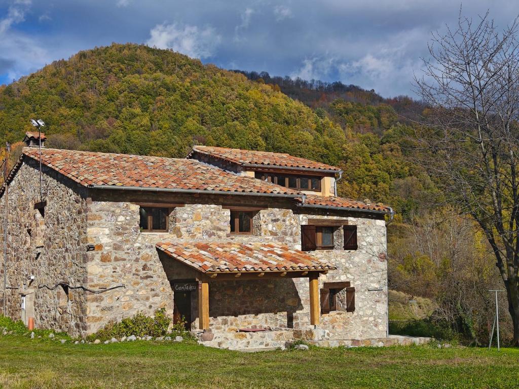a stone building with a mountain in the background at Can Tadeu in Camprodon