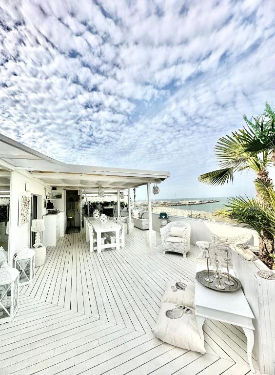 a deck with white furniture and a view of the ocean at La Terrazza in Senigallia
