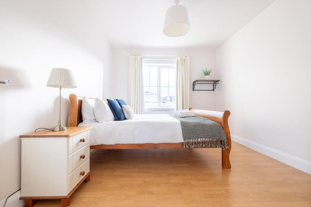a white bedroom with a bed and a window at Beach Park House in Downings
