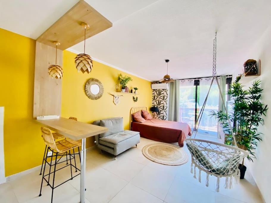 - un salon avec des murs jaunes et un canapé dans l'établissement Studio Boho Clim Parking terrasse, à Nîmes