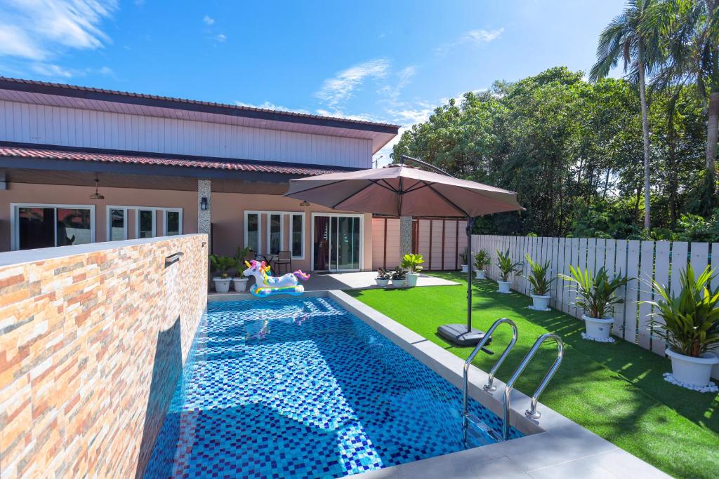 una piscina con un ombrellone in un cortile di D' Village Cottage 2 - Private Pool Villa a Pantai Cenang