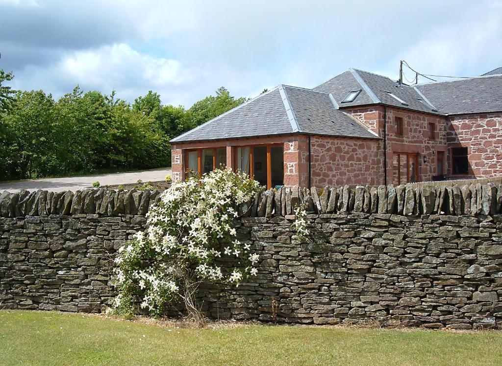 a stone wall in front of a brick house at Plovermuir Cottage in Kirriemuir