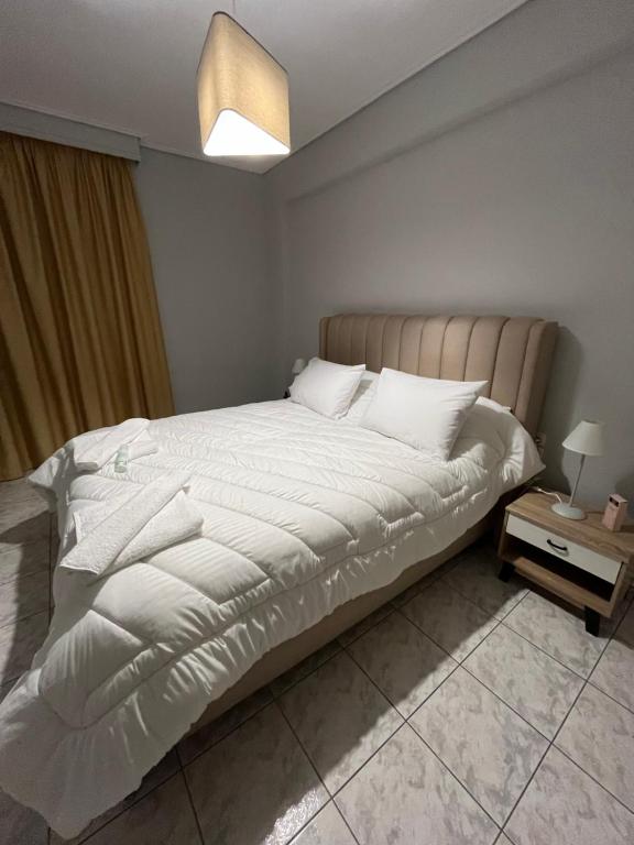a bedroom with a large bed with white sheets at Linda's Apartment in Tríkala