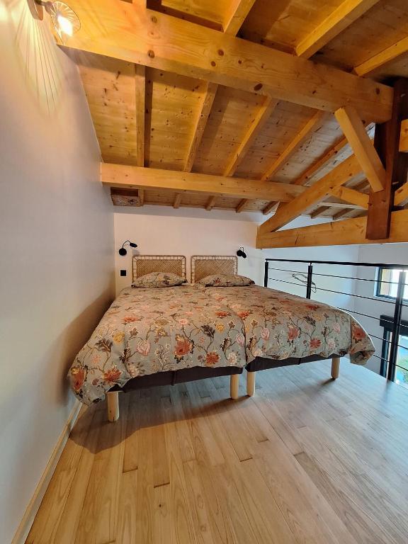 une chambre avec un lit dans une pièce avec des plafonds en bois dans l'établissement Lodge les ombelles, à Coutras