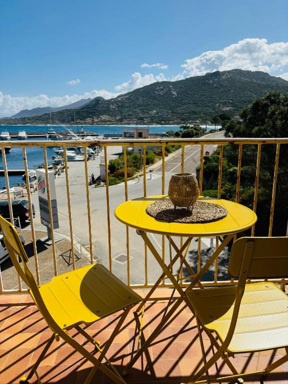 une table et des chaises jaunes sur un balcon avec vue dans l'établissement appartement 2 chambres vue mer imprenable marine de Sant Ambrogio LUMIO, à Lumio
