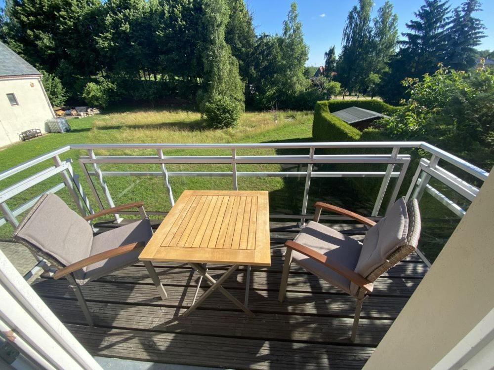 a wooden table and chairs on a deck at Ferienwohnung Kirchbergaussicht in Olbersdorf