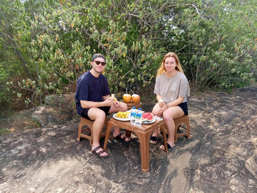 a man and woman sitting around a table with food on it at Nice View Safari villa in Udawalawe