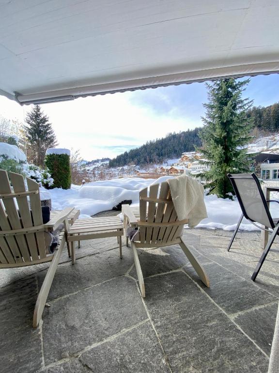 two chairs and a table on a patio in the snow at house & living junbi in Laax