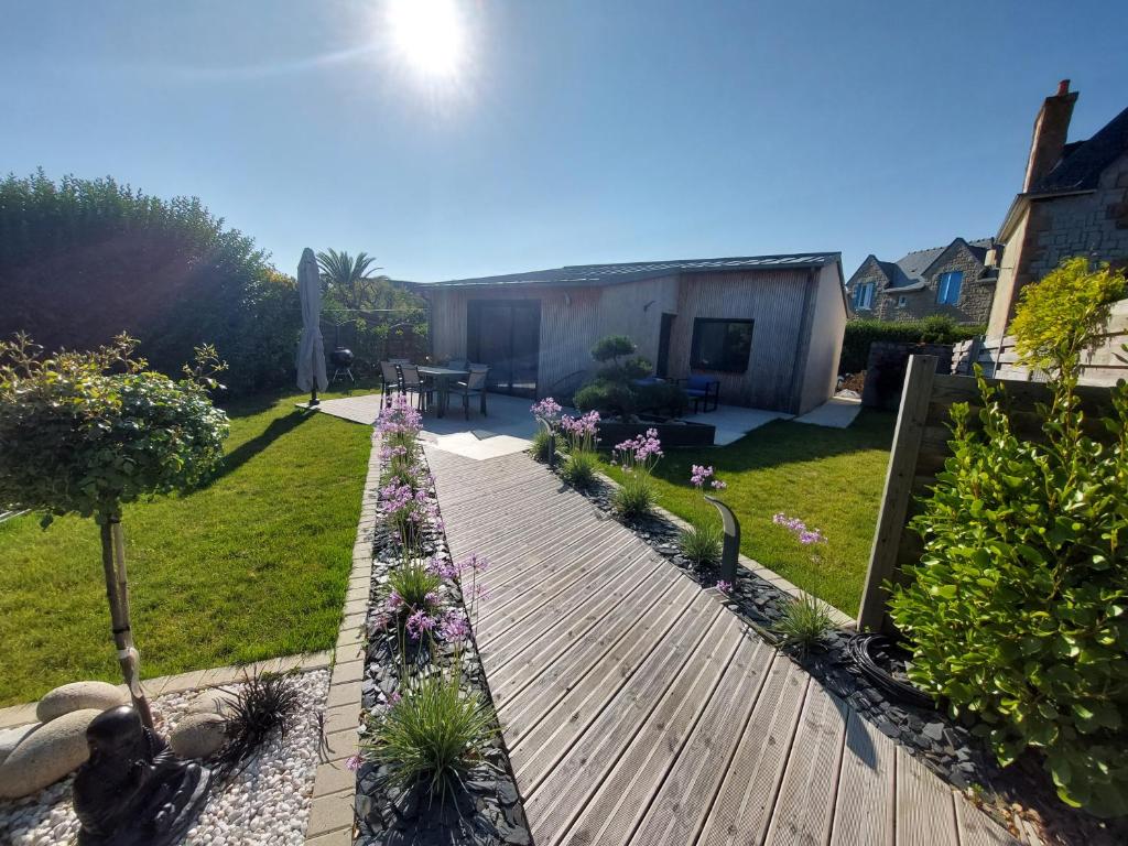 Un jardín con un camino de madera con flores y plantas. en Île Grande, Location maison saisonnière chez Dom et Cathy C, en Pleumeur-Bodou