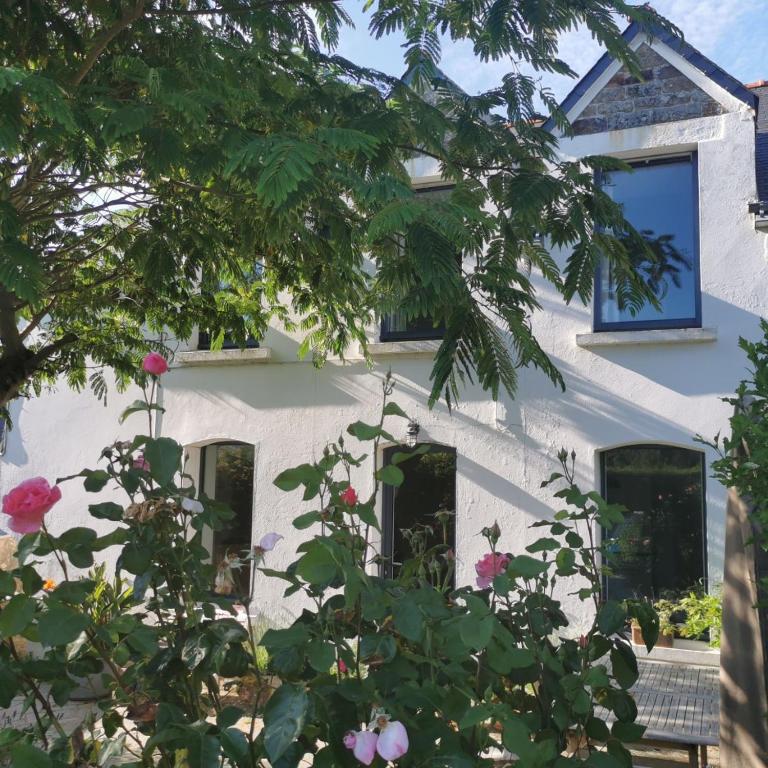 une maison blanche avec des fleurs devant elle dans l'établissement Maison cosy, à Larmor-Baden