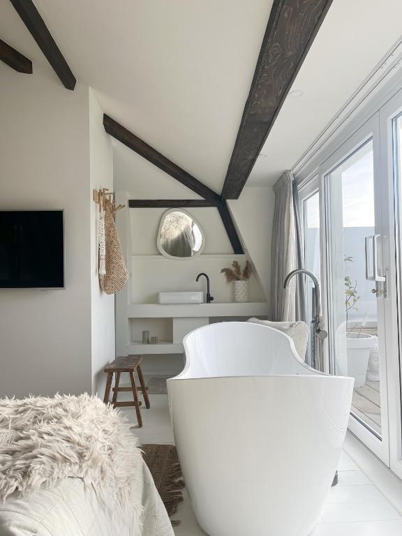eine weiße Badewanne in einem Schlafzimmer mit Fenster in der Unterkunft Het sfeerhuis aan zee in Vlissingen