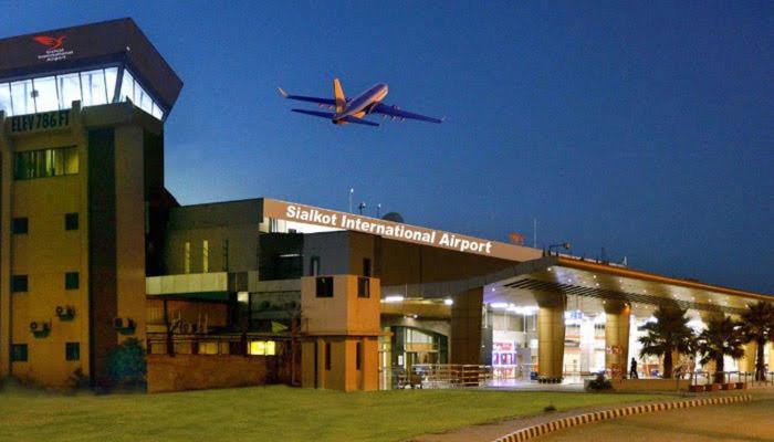 an airplane is flying over a building with an airport at Sialkot International Airport Guesthouse in Sambriāl
