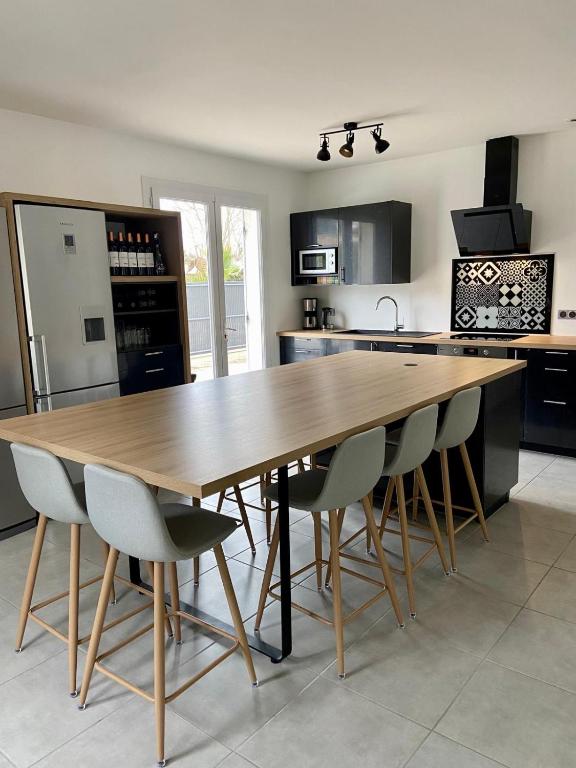 une cuisine avec une grande table et des chaises en bois dans l'établissement Maison familiale dans le Médoc, à Le Pian-Médoc