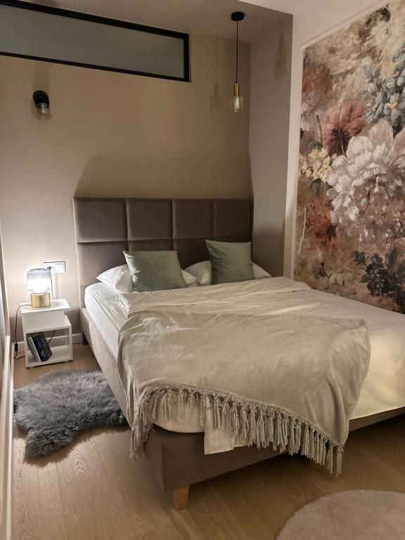 a bedroom with a large bed with a painting on the wall at Malinowy Apartament in Zamość