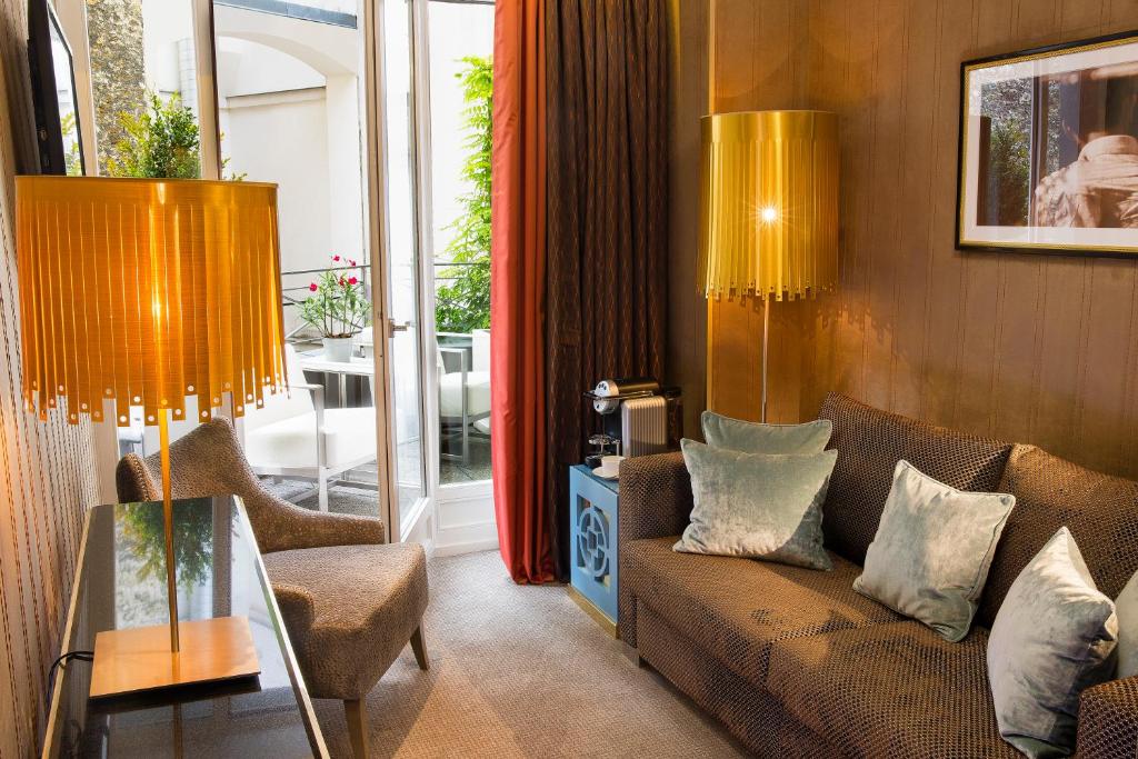 un soggiorno con un divano e un tavolo con sedie di Hôtel Baume a Parigi