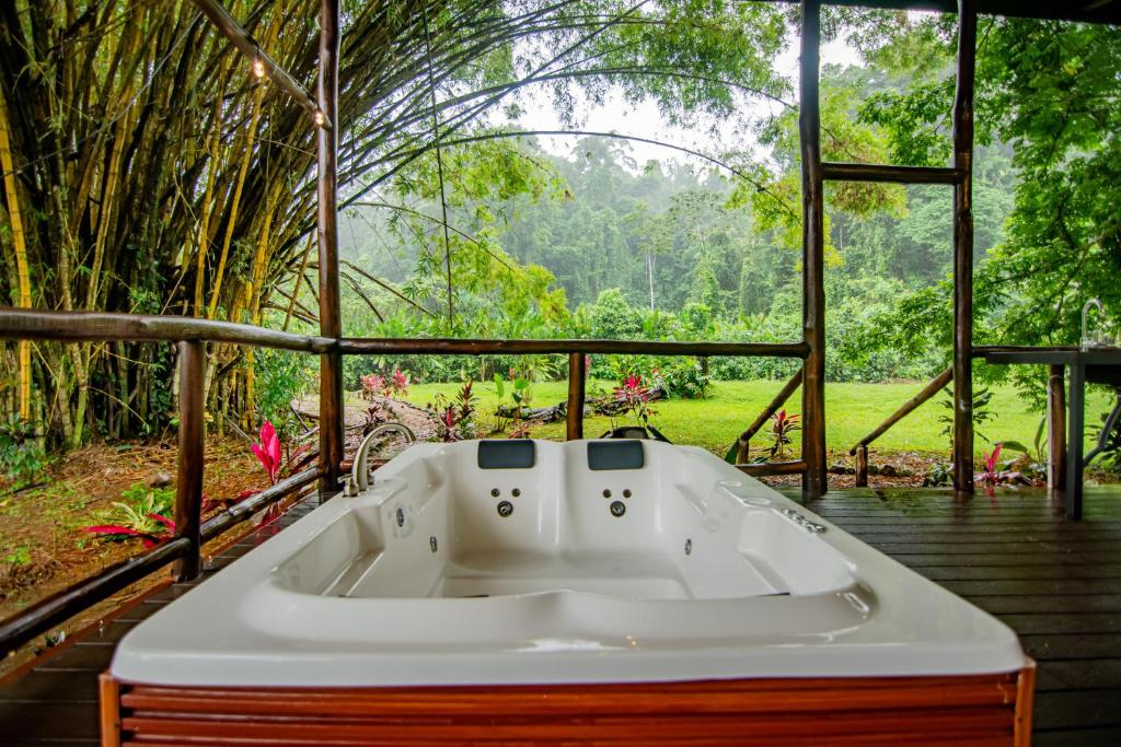 a bath tub on a deck with a view of a forest at Cabaña Los Tucanes in Fortuna