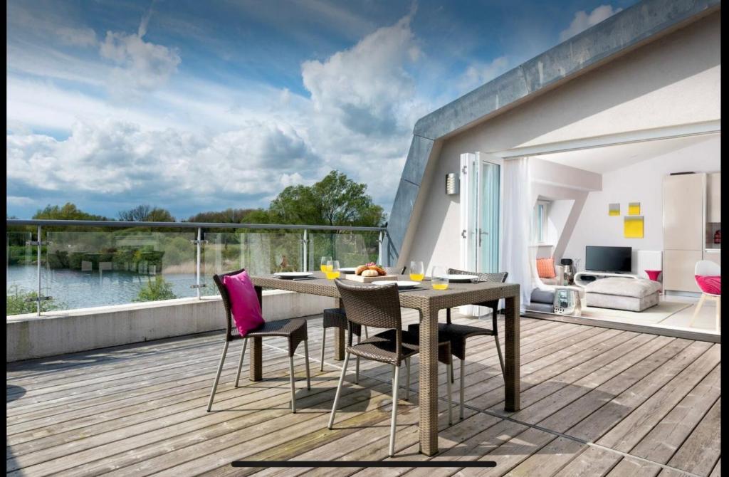 a wooden deck with a table and chairs on a balcony at Willow Warbler - HM112 - Lower Mill Estate Penthouse Apartment with Spa Access in Somerford Keynes