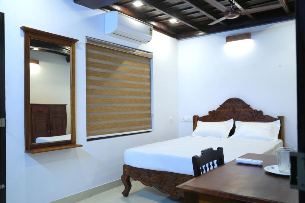 a bedroom with a bed and a table and a window at Poovar Heritage Homes in Pūvār