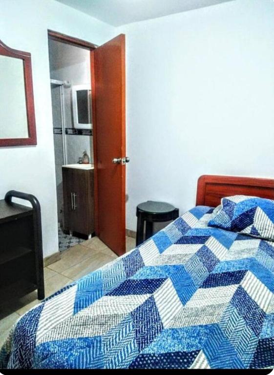 a bedroom with a blue and white quilt on a bed at My second house in Manizales