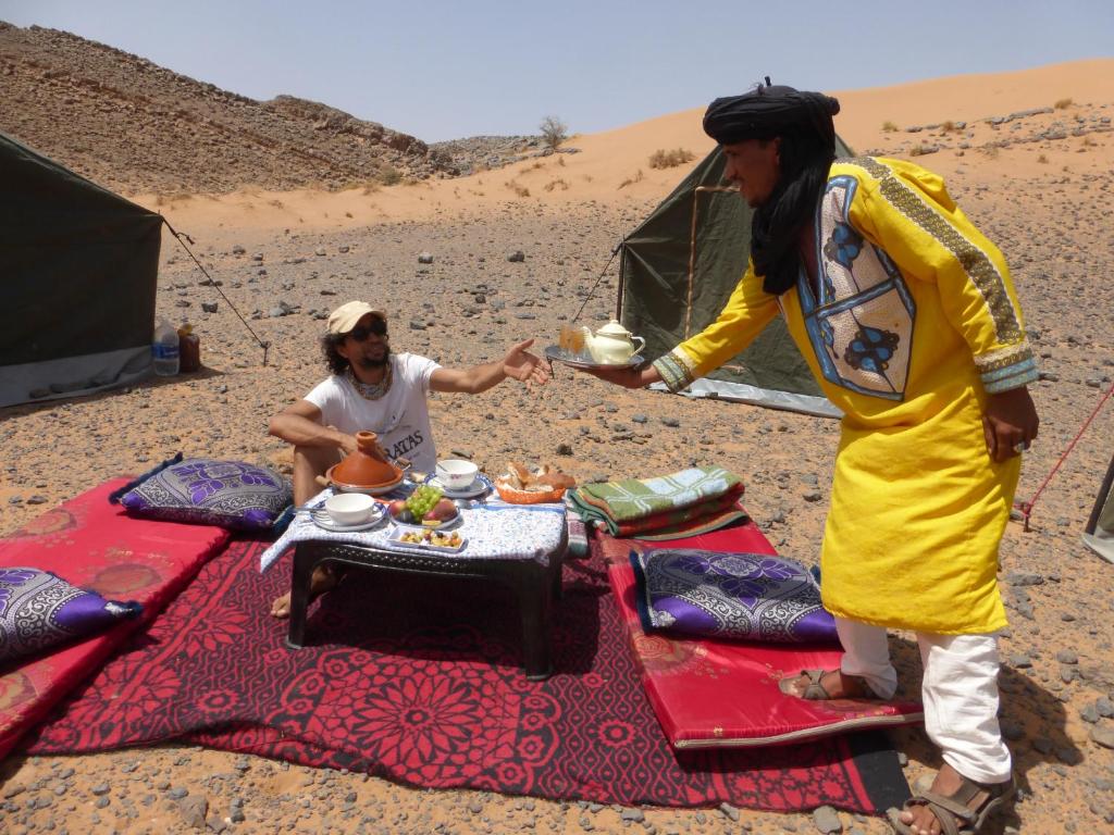 two women standing next to a table in the desert at Desert Backpackers Camp in Merzouga