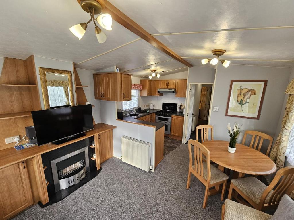 a living room with a table and a kitchen at 8 Berth Caravan - North Shore Holiday Park Skegness 3 Bedrooms in Skegness
