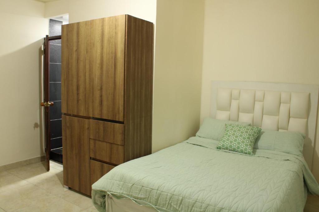カリにあるCasa Esperanzaのベッドと木製のキャビネットのある寝室