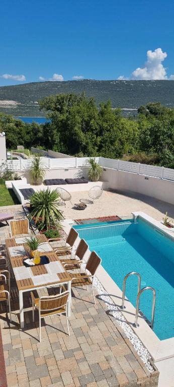 a patio with a pool and chairs and a table and a swimming pool at Villa Korta Regina in Ston