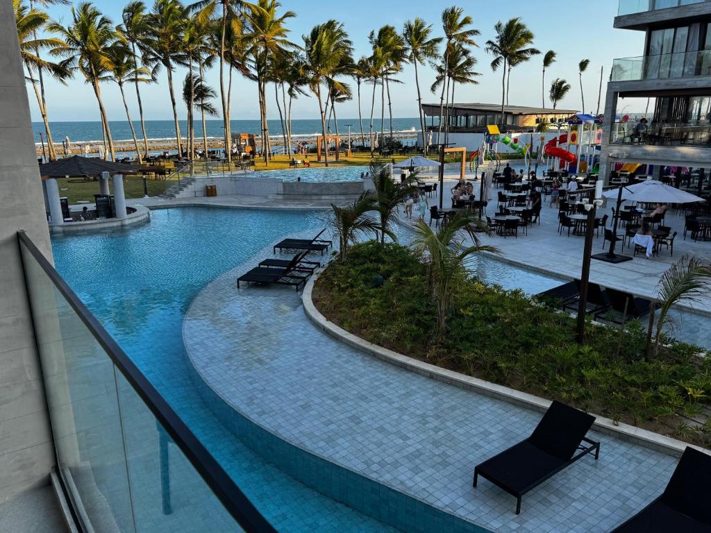 una piscina con sedie e palme in un resort di Porto Alto Resort a Ipojuca