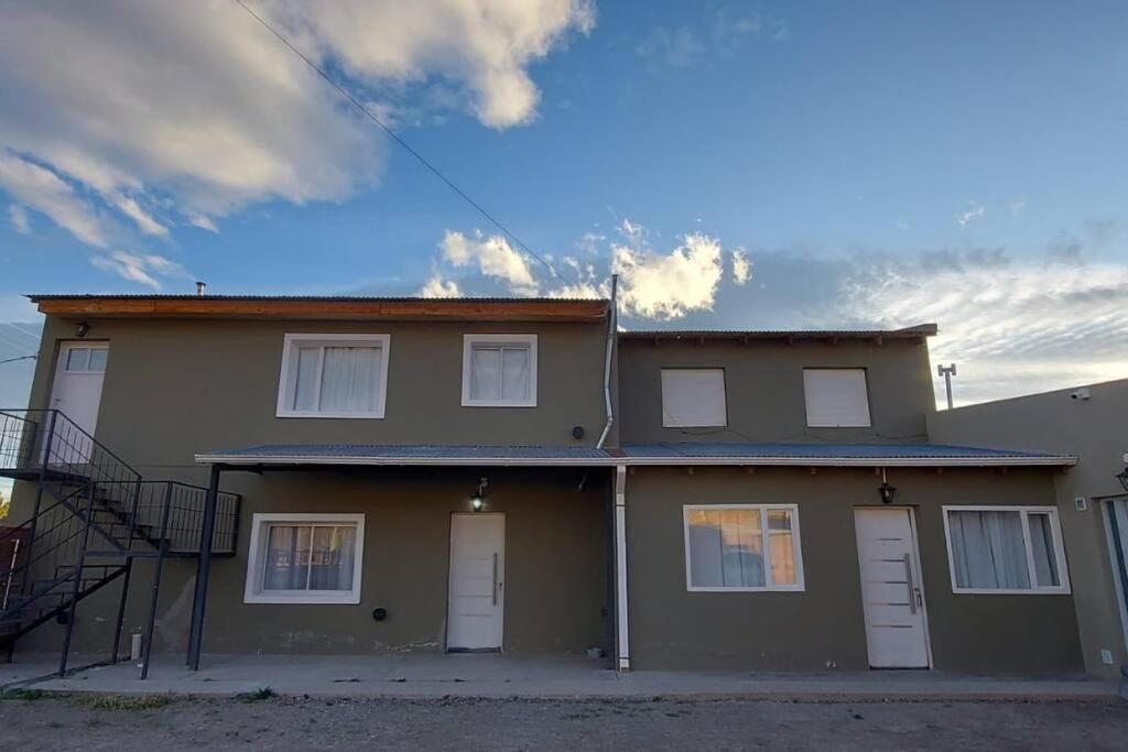ein Haus mit weißen Türen und einem Himmel in der Unterkunft La Fueguina Departamento 2 en Gobernador Gregores in Gobernador Gregores