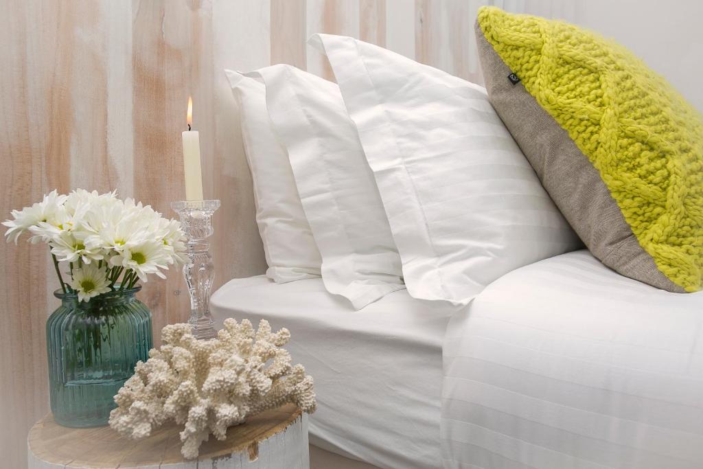 a white vase filled with flowers next to a white pillow at 10 Hastings Street Boutique Motel in Noosa Heads