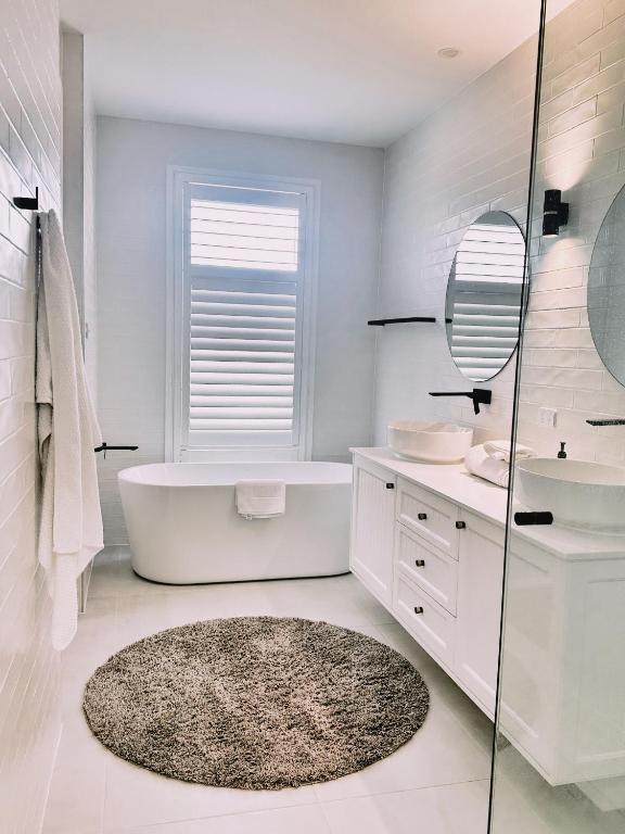 a bathroom with a tub and a sink and a mirror at Team Luxury Home for Short or Long Stays in Muswellbrook