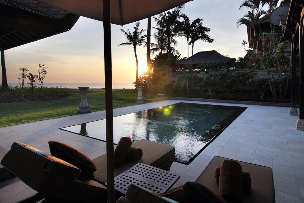 a view of a pool with chairs and an umbrella at Villa Nirwana in Tanah Lot