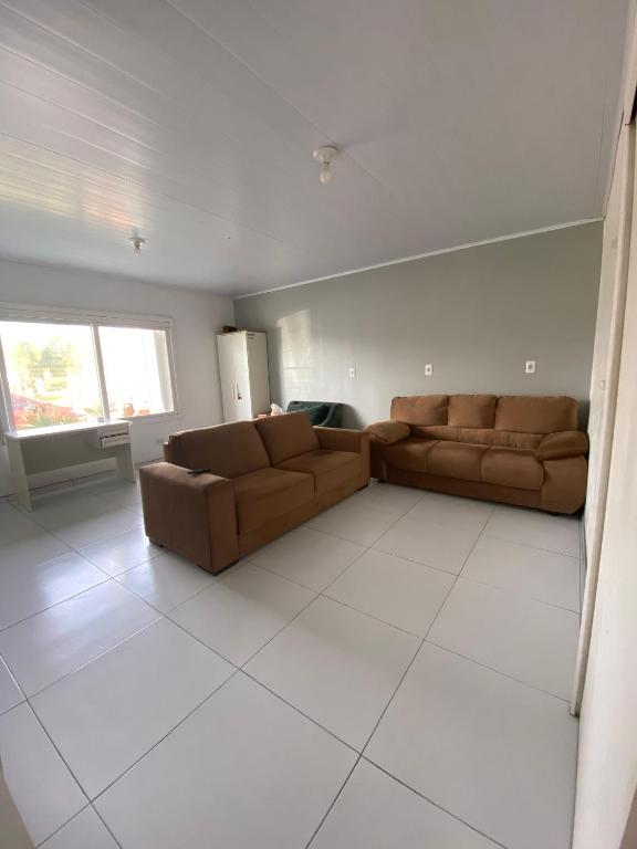 a living room with two brown leather couches at Casa Grande 400m da praia do lado do centrinho in Imbé