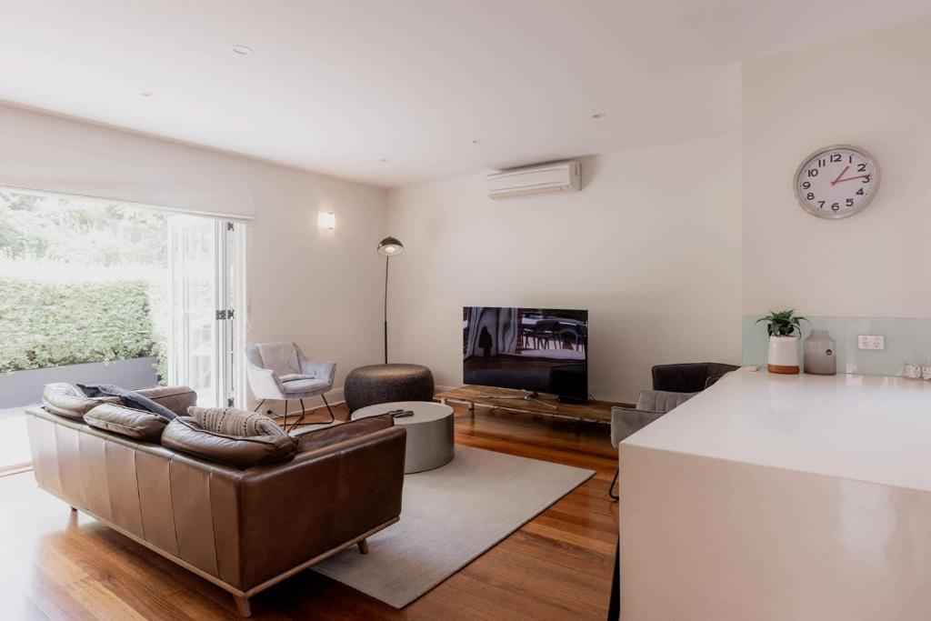 Una sala de estar con un sofá y un reloj en la pared. en Modern Home in Sandy Bay - Sleeps 8 Guests, en Sandy Bay