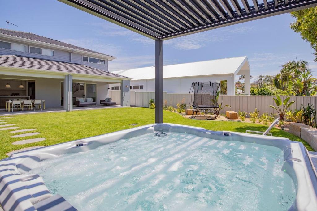 a hot tub in the backyard of a house at Shoreline Luxe - Refined Beachside Elegance with Spa in Caves Beach