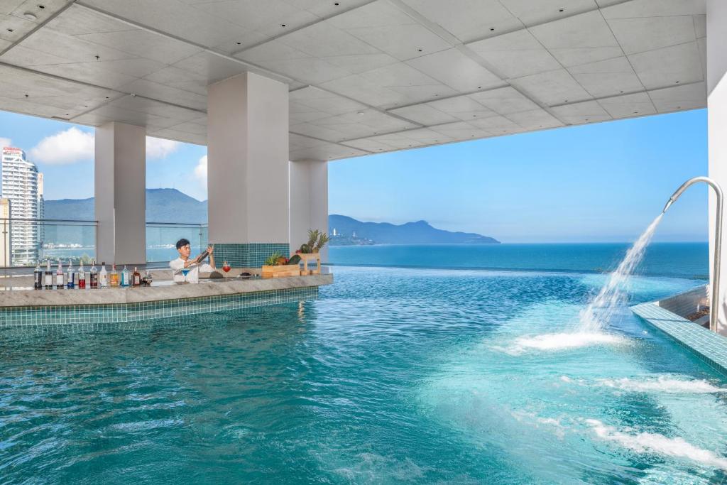 a swimming pool with a fountain in the water at Awaken Da Nang Hotel in Danang