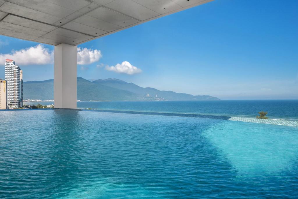 a swimming pool with a view of the ocean at Awaken Da Nang Hotel in Danang