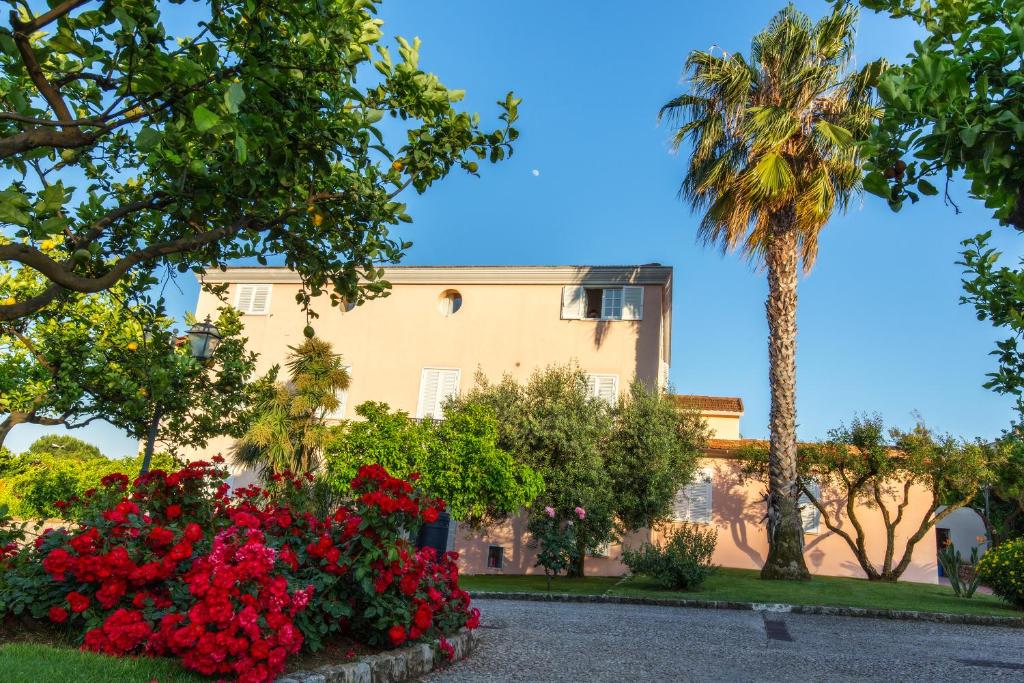 a building with red flowers and a palm tree at Villa Irlanda Grand Hotel in Gaeta