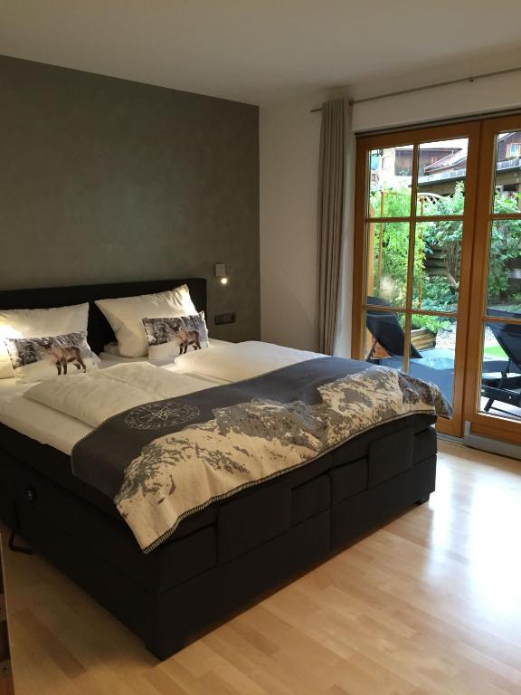 a bedroom with a large bed and a large window at Boutiqueferienwohnung Schnapshäusel in Oberstdorf