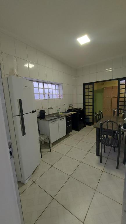a kitchen with a refrigerator and a table and chairs at Casa térrea no centro ideal para famílias e trabalho in Mogi das Cruzes