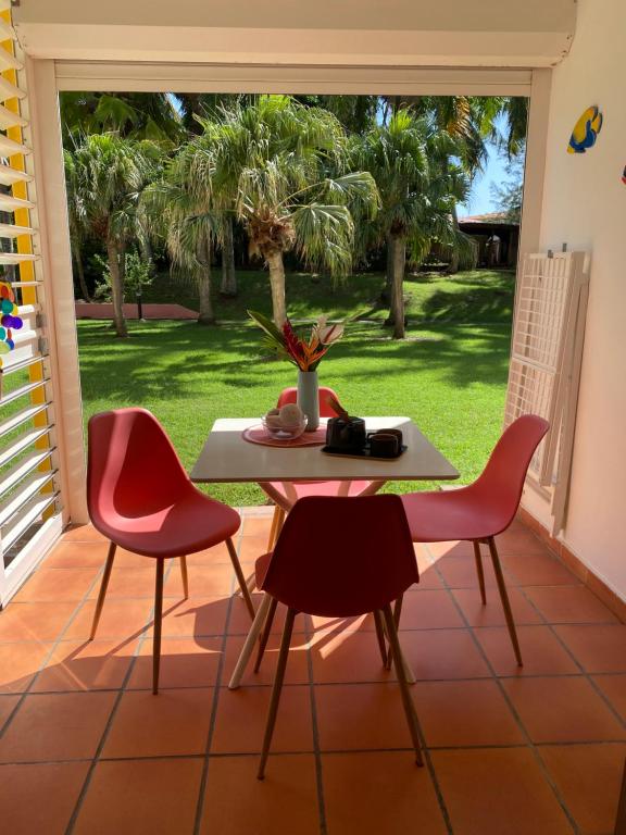 een tafel en stoelen op een patio met een palmboom bij Bienvenue au Ti Frangipanier in Saint-François