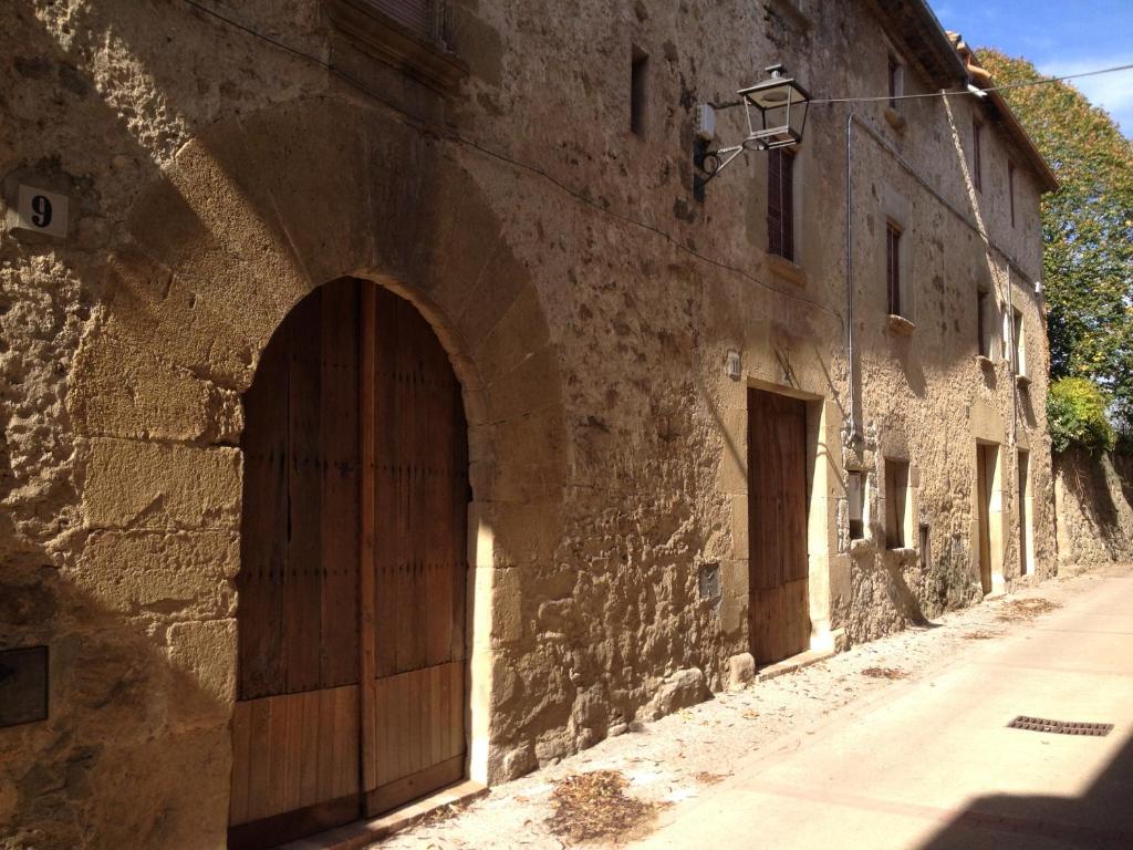 een oud stenen gebouw met een grote houten deur bij Ca La Remei i Can Benet in Els Hostalets d'en Bas
