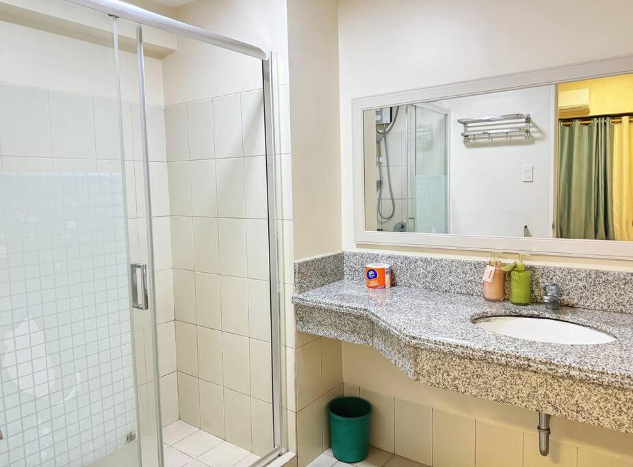 a bathroom with a sink and a shower with a mirror at 马尼拉湾三房公寓 in Manila