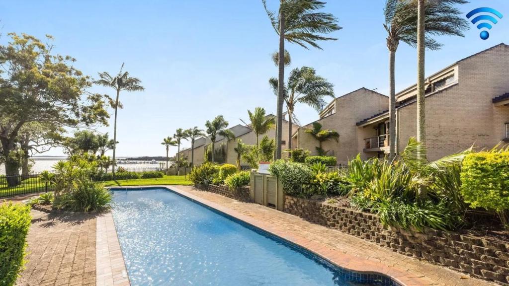 an image of a swimming pool in front of a house at Sunset at The Moorings in Soldiers Point