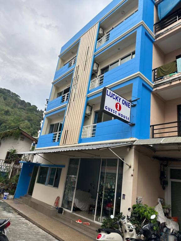 Lucky One Guesthouse في شاطيء باتونغ: مبنى أزرق اللون عليه لافتة مكتوب عليها فندق لاكي وان