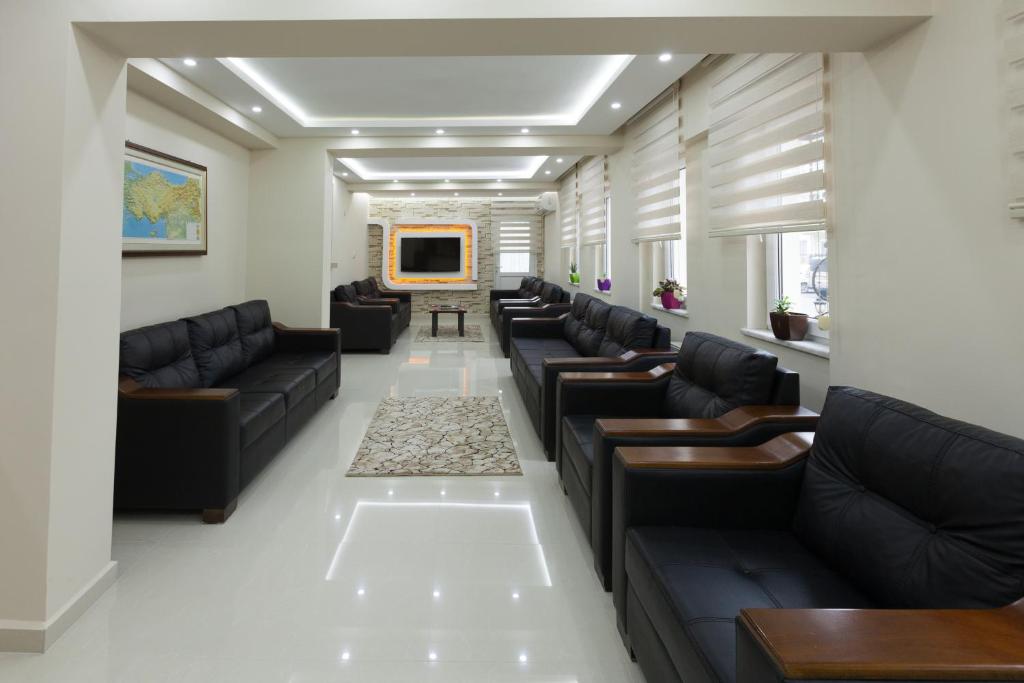 una sala de espera con sofás de cuero negro y TV en Gizem Pansiyon, en Canakkale