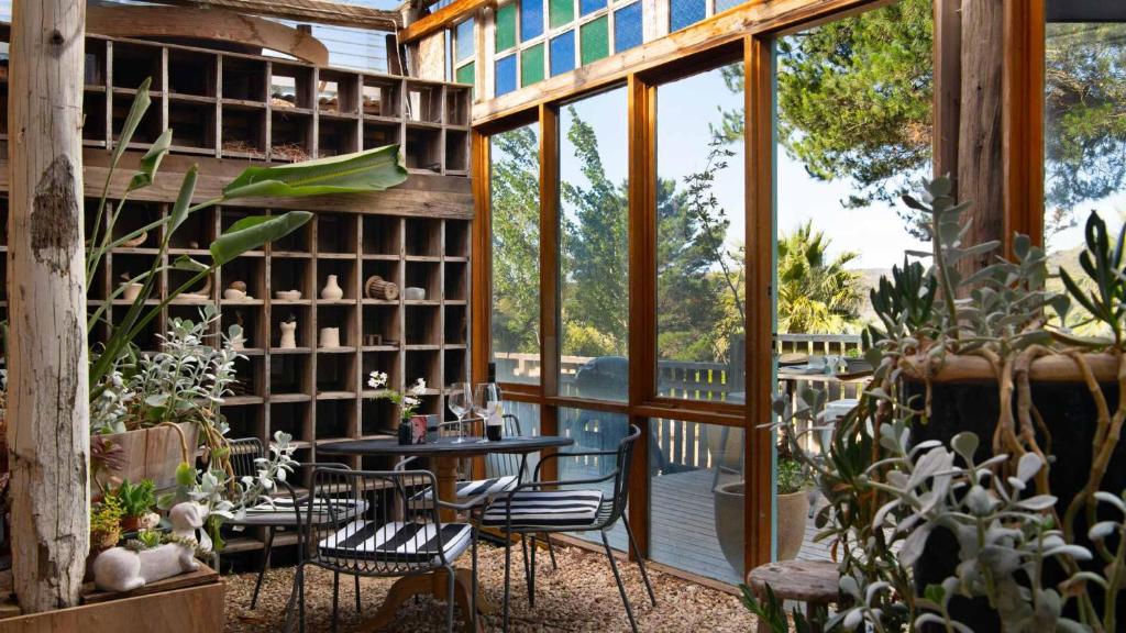 un patio con mesa, sillas y algunas plantas en Artists Garden Cottage, en Hepburn Springs