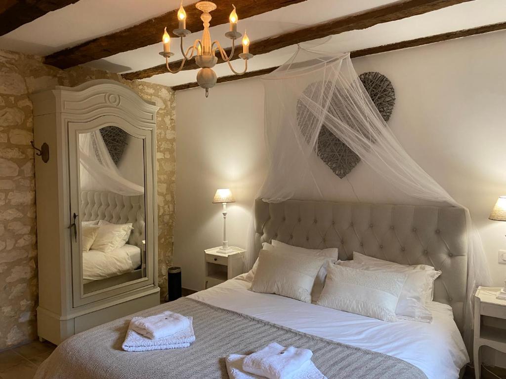 - une chambre avec un lit blanc et un grand miroir dans l'établissement Luxury Gîte - L'Ancien Chai, à Eymet