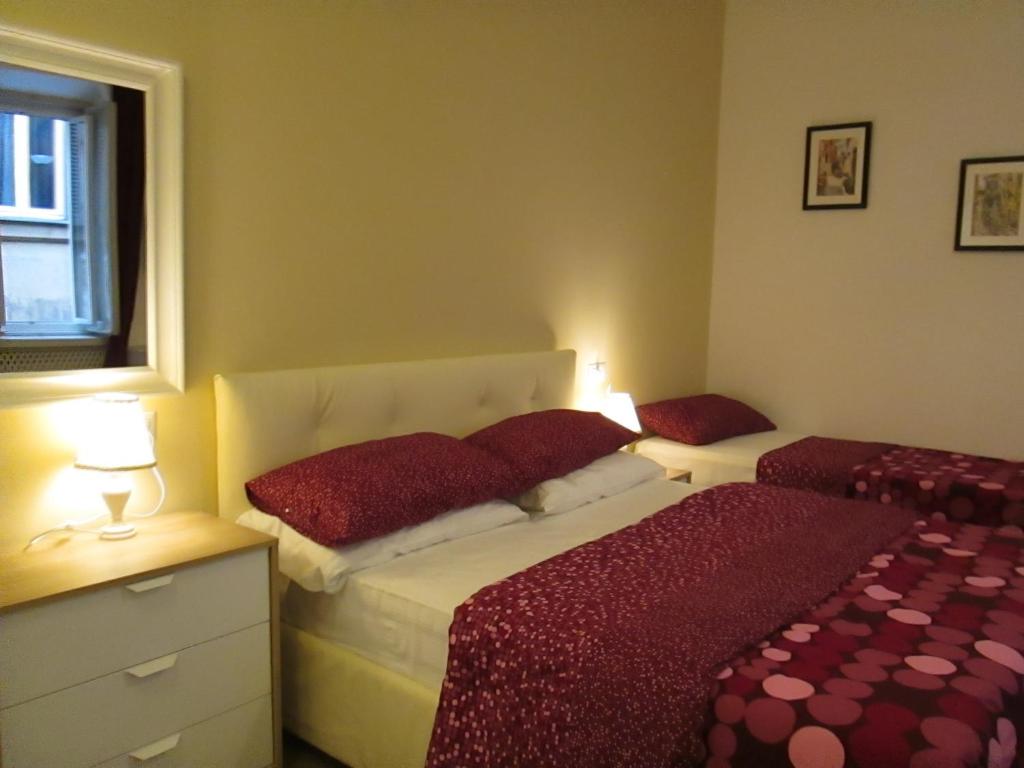 1 dormitorio con 2 camas con almohadas rojas y ventana en Trevi Elegance Suite, en Roma